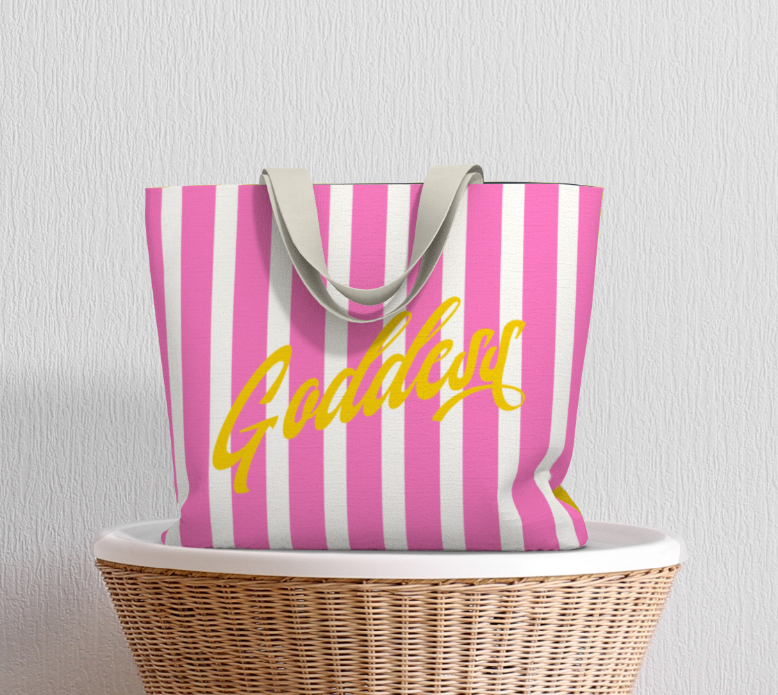 Our signature stripes luxe tote shown in a bold pink and yellow with the word "Goddess" on the bag, features 2 interior pockets and a navy blue lining.