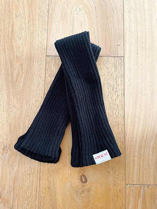 Black knee high leg warmers with a Signature Sweat Goddess tag on one leg