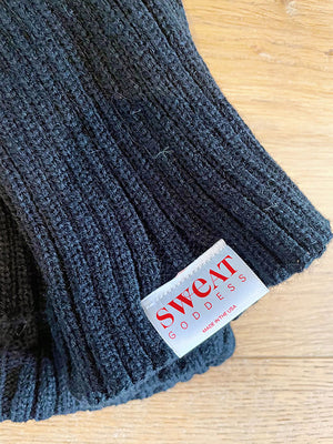 Black knee high leg warmers with a Signature Sweat Goddess tag on one leg