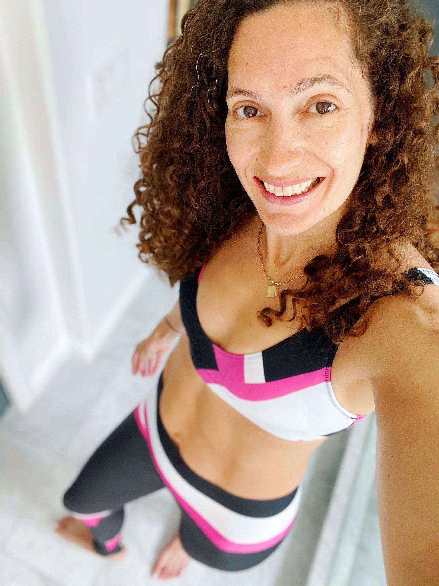 Our signature color block style in a vibrant pink, black and white with the word "Goddess" down one leg, on these high-waisted compression leggings shown here with matching bralette.