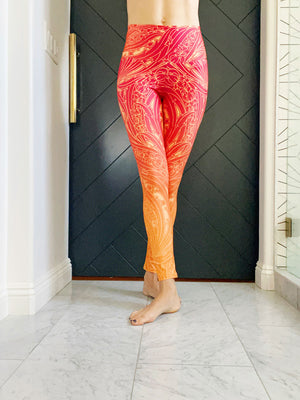 A vibrant orange ombre color palette with a beautiful art deco print on these high-waisted compression leggings.