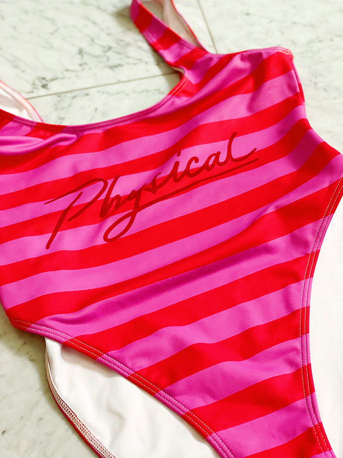 Retro swim/body suit in pink and red stripes with the word physical on the front.