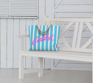 Our signature stripes luxe tote shown in a bold pink and blue with the word "Goddess" on the bag, features 2 interior pockets and a navy blue lining.